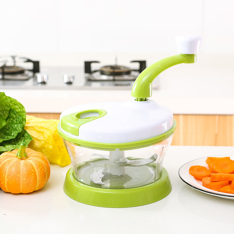 Green and white kitchen tool on a counter with vegetables and carrots in the background