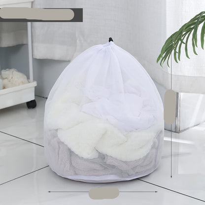 Two white mesh laundry bags filled with laundry standing in front of a washing machine with a person partially visible in the background.