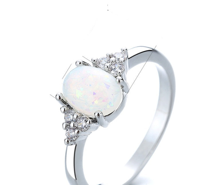 Silver ring with a white gemstone and measurements on a white background