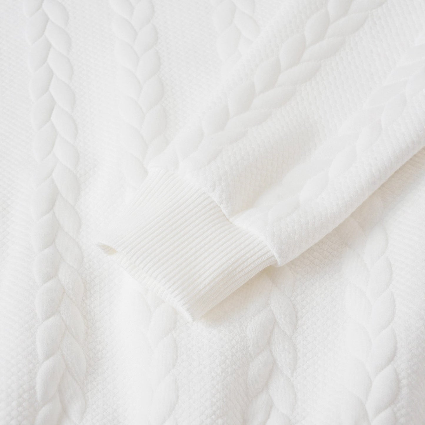 Close-up of a white cable knit sweater texture