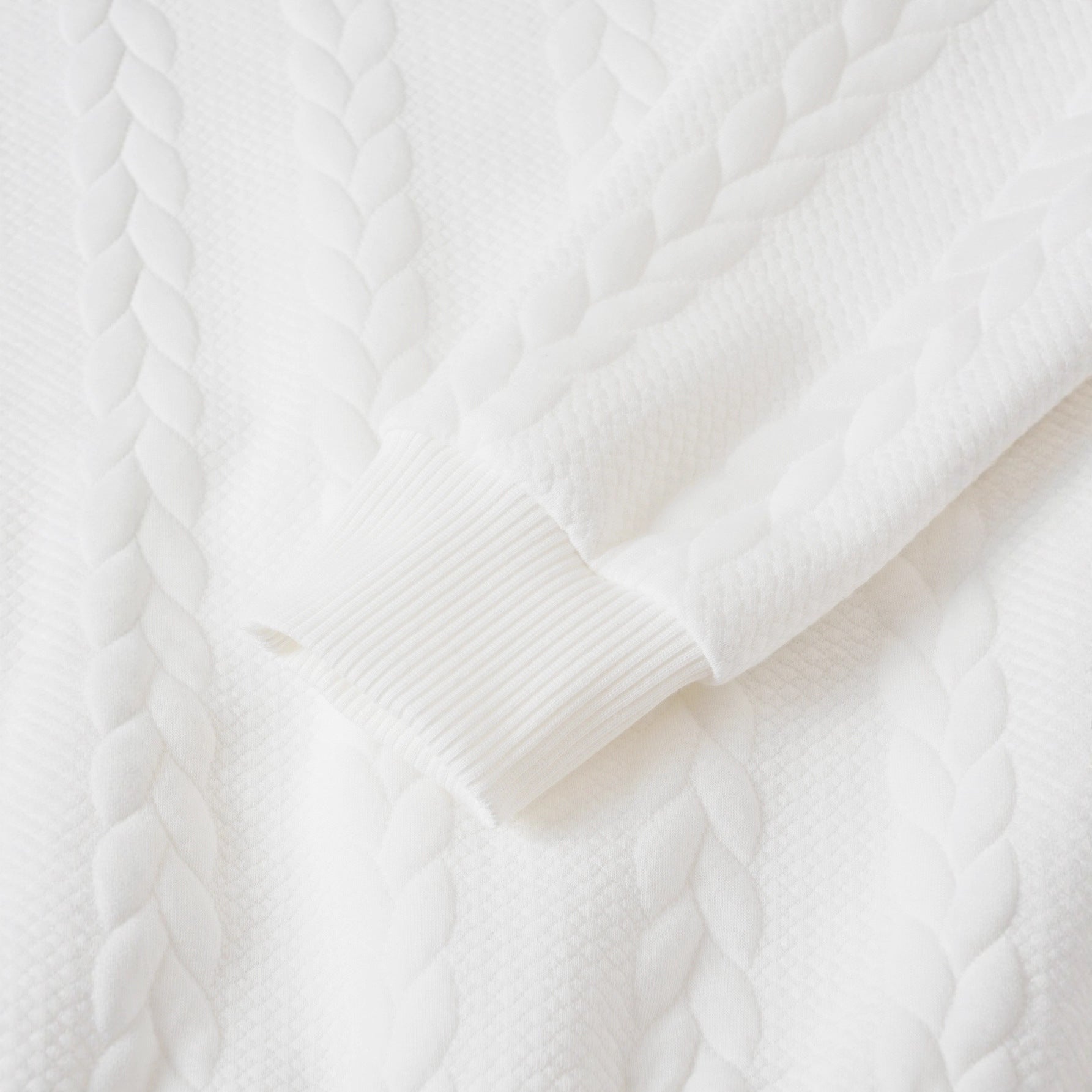 Close-up of a white cable knit sweater texture
