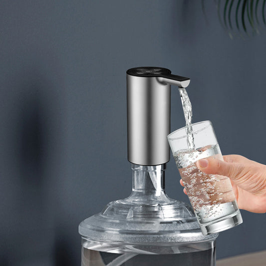 Hand holding a glass under a self-cleaning faucet with water flowing.