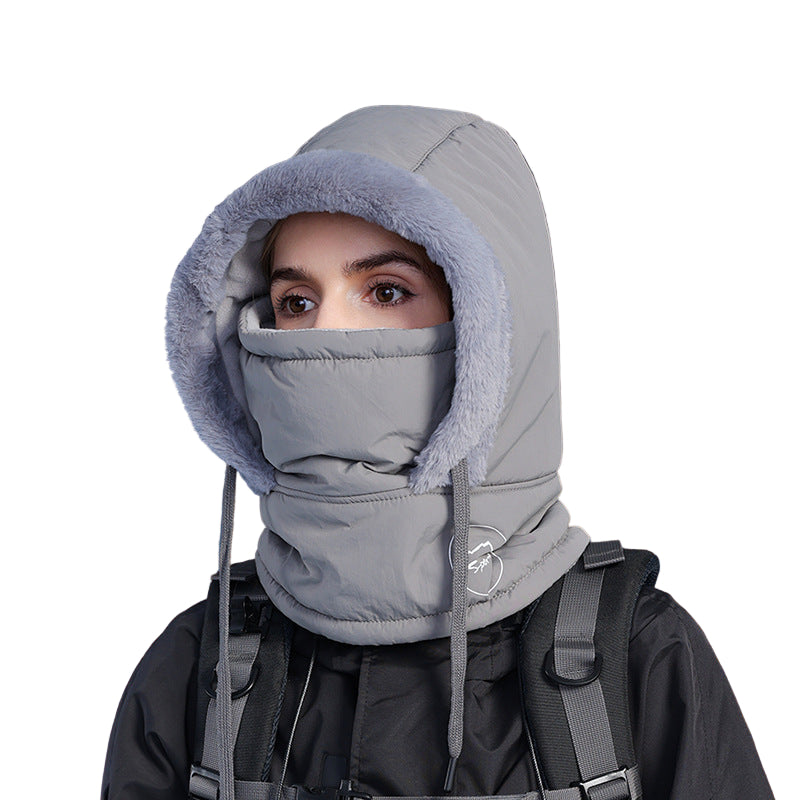 Person wearing a gray winter hood and face mask against a snowy night background