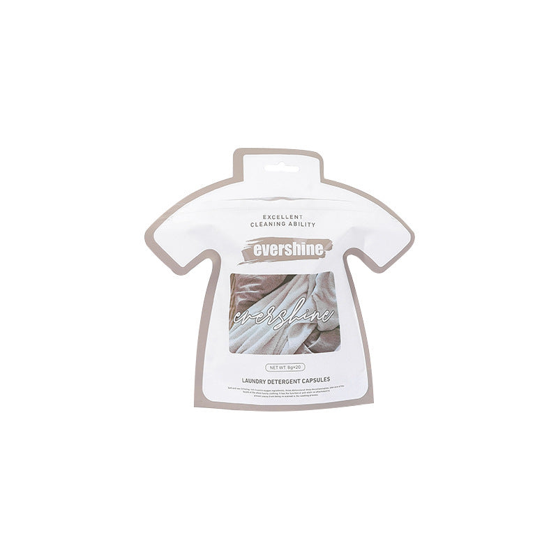 Packaging of laundry gel beads in the shape of a shirt placed on a washing machine, with plants and laundry in the background.