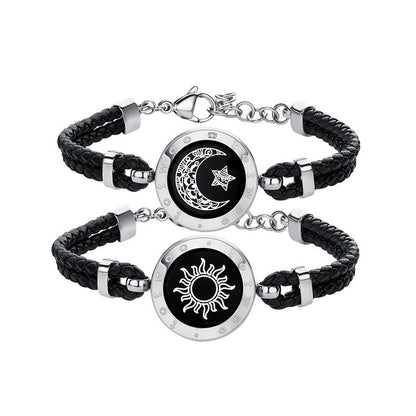 Pair of black braided bracelets with silver circular charms featuring celestial designs on a white background.