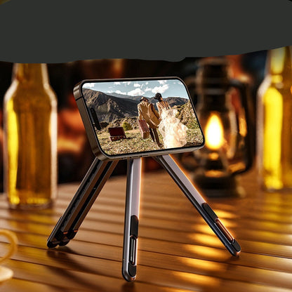 Phone stand on a wooden table with a scenic phone screen, surrounded by bottles and a lantern.