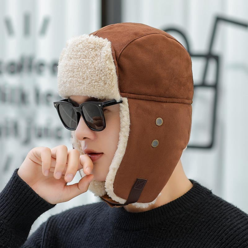 Person wearing a brown fur-lined helmet with sunglasses on a blurred background
