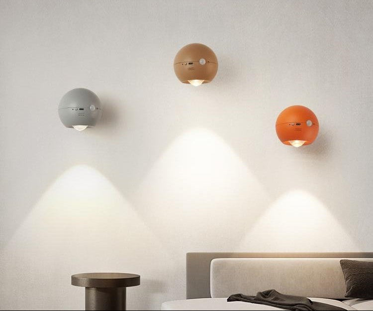 Three spherical wall lights in different colors on a neutral wall.