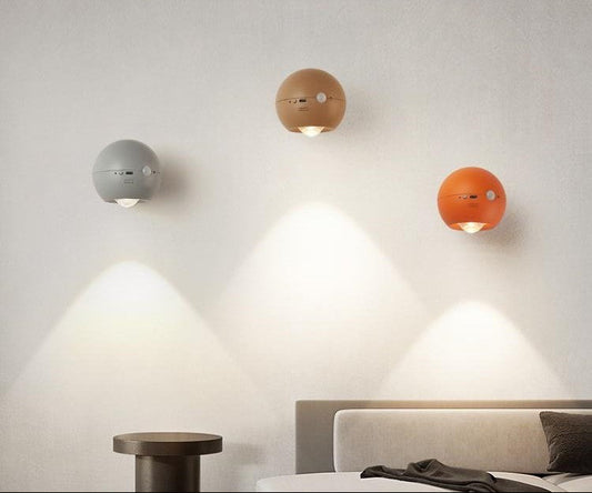 Three spherical wall lights in different colors on a neutral wall.