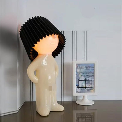 Decorative lamp shaped like a person with a black textured head on a white background