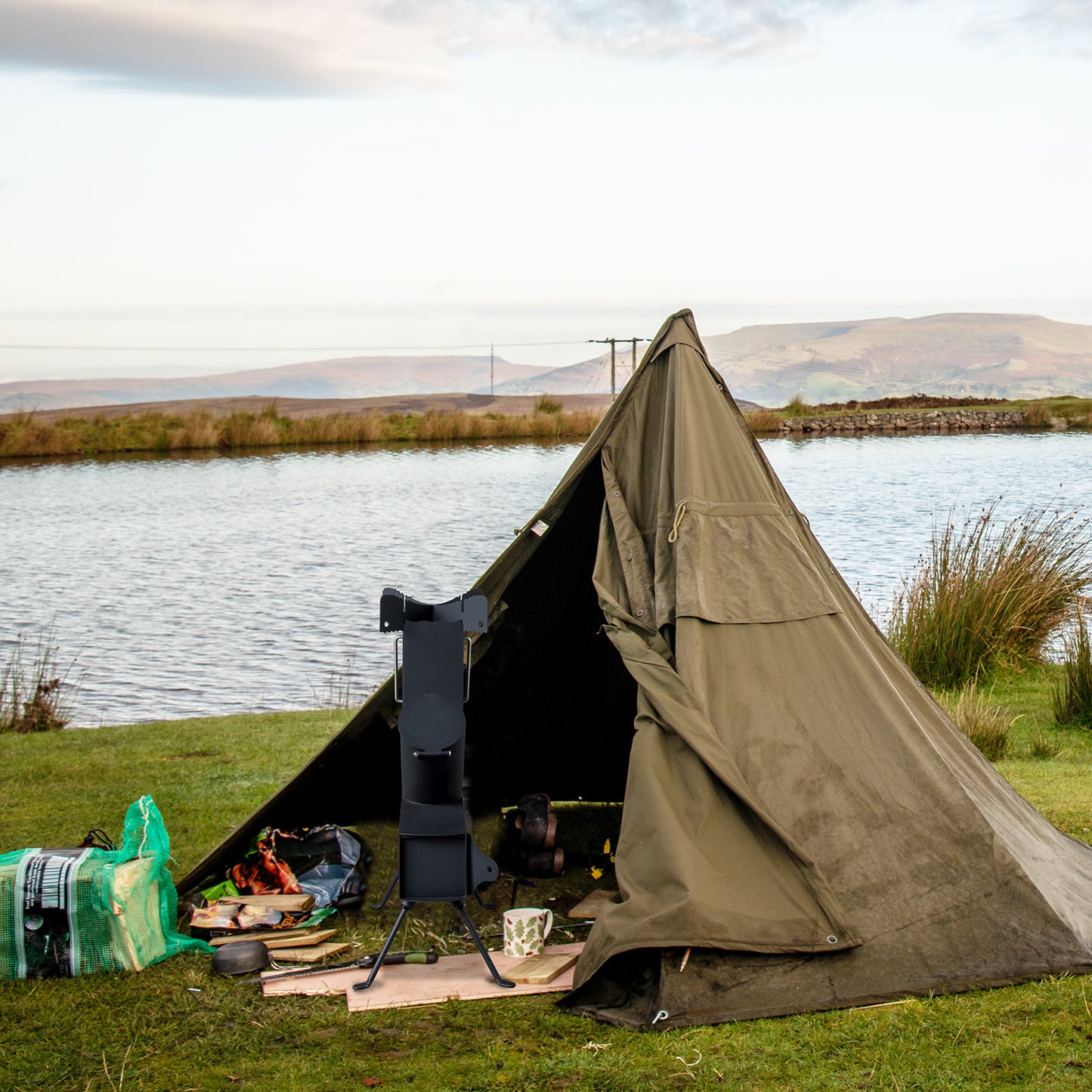 Brown tent set up by a body of water with equipment around