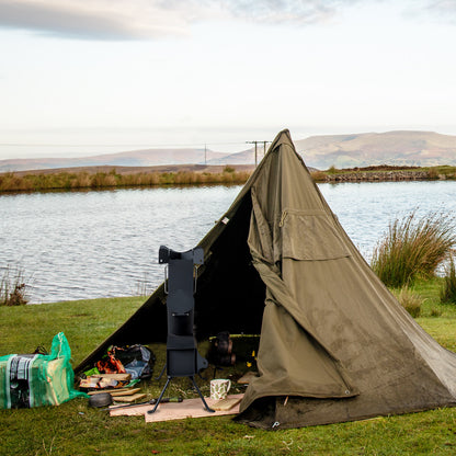 Brown tent set up by a body of water with equipment around
