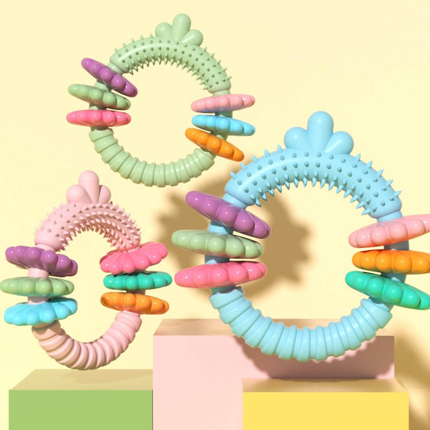 Colorful silicone teething rings on a pastel yellow background