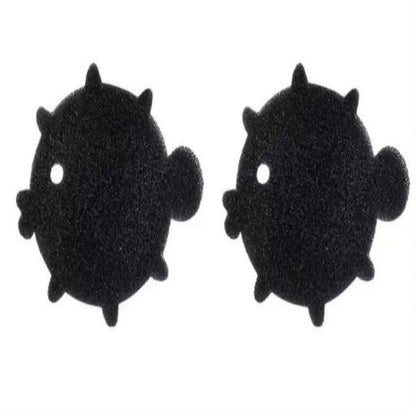 A black sponge shaped like a bear is shown being used to pick up pet hair from a beige surface, demonstrating its use as a cleaning tool.