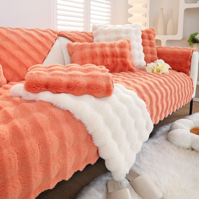 Orange and white textured blanket draped over a sofa in a cozy living room.