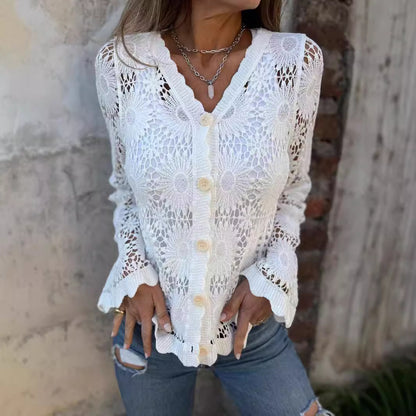 Woman wearing a white lace cardigan with a stone wall background