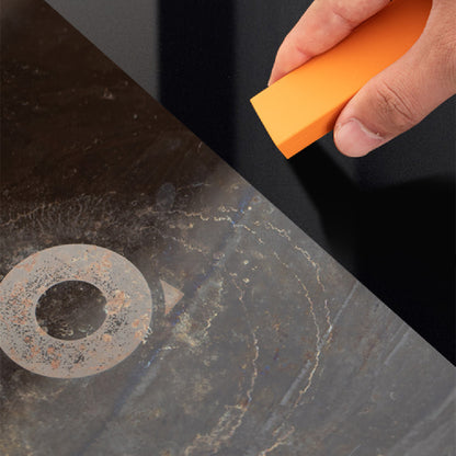 Hand using an orange sponge to clean a rusty metal surface