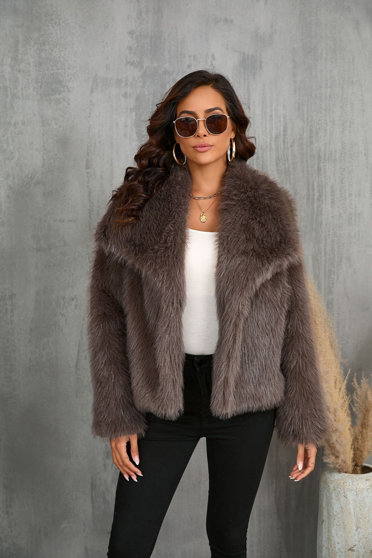 Woman wearing a fur coat against a gray concrete wall