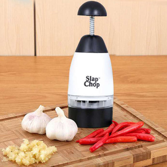 Slap Chop garlic chopper on a wooden cutting board with garlic and red peppers.