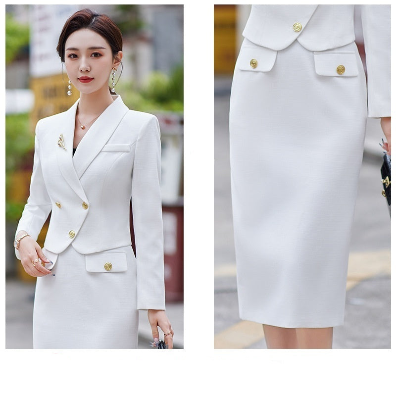 A woman in a white leisure formal suit with a blazer and a skirt, featuring long sleeves and gold buttons, standing outdoors.