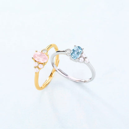 Two rings, one gold and one silver, each with a central gemstone on a light background