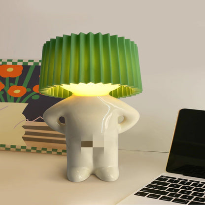 White elephant-shaped lamp with green pleated shade on a desk next to a laptop