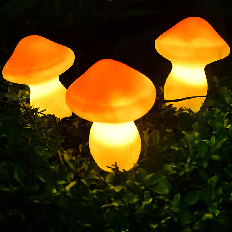 Three illuminated mushroom-shaped lights on grass at night