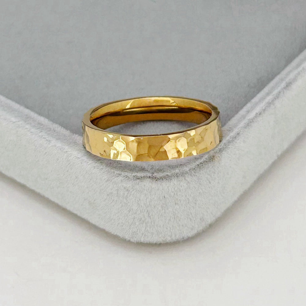 Gold ring with a textured surface on a gray cushion