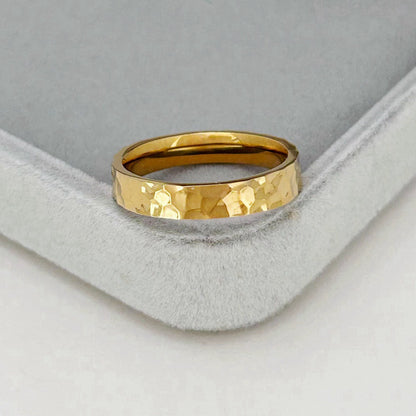 Gold ring with a textured surface on a gray cushion