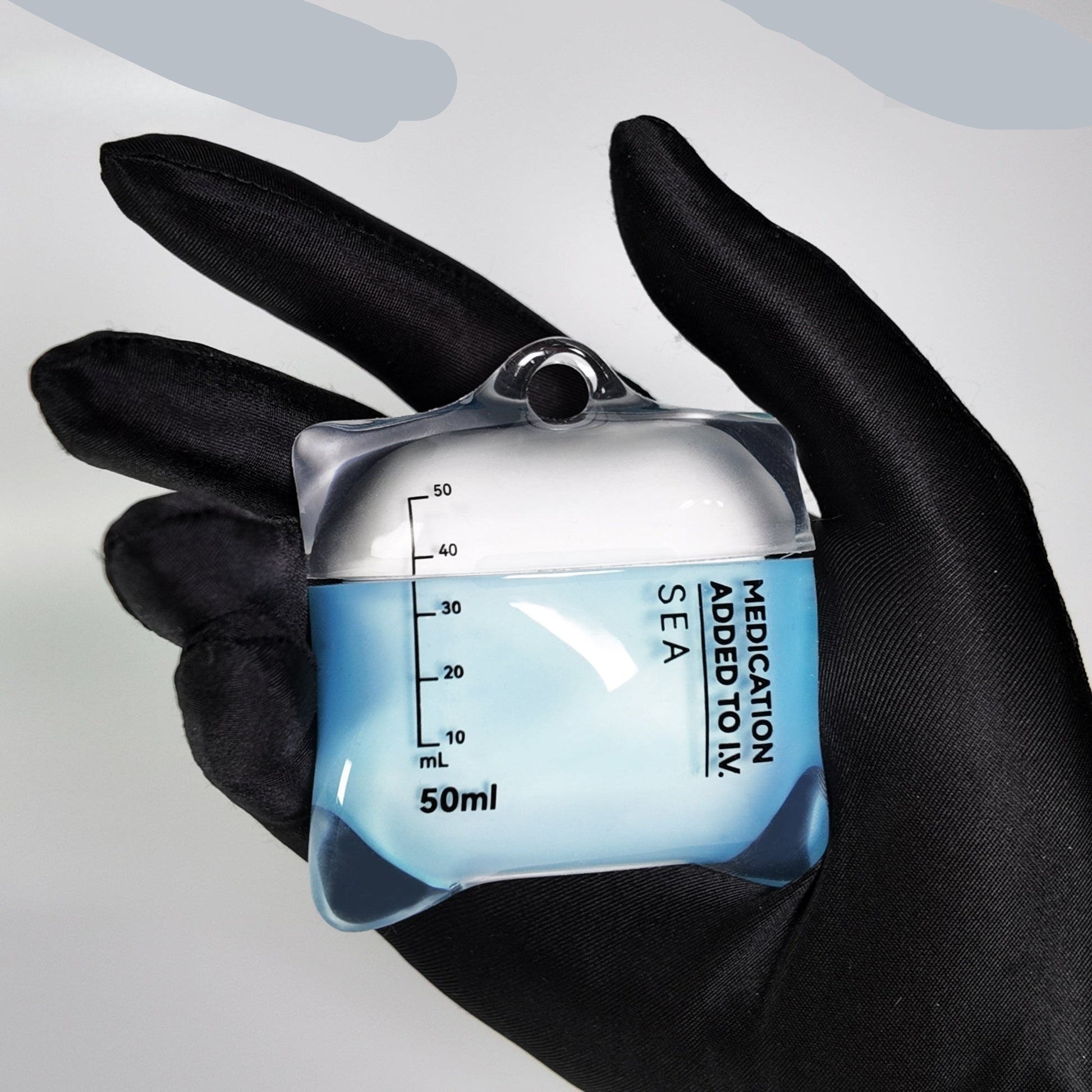 AirPods case designed like a medical container with measurement markings, held in a black glove.