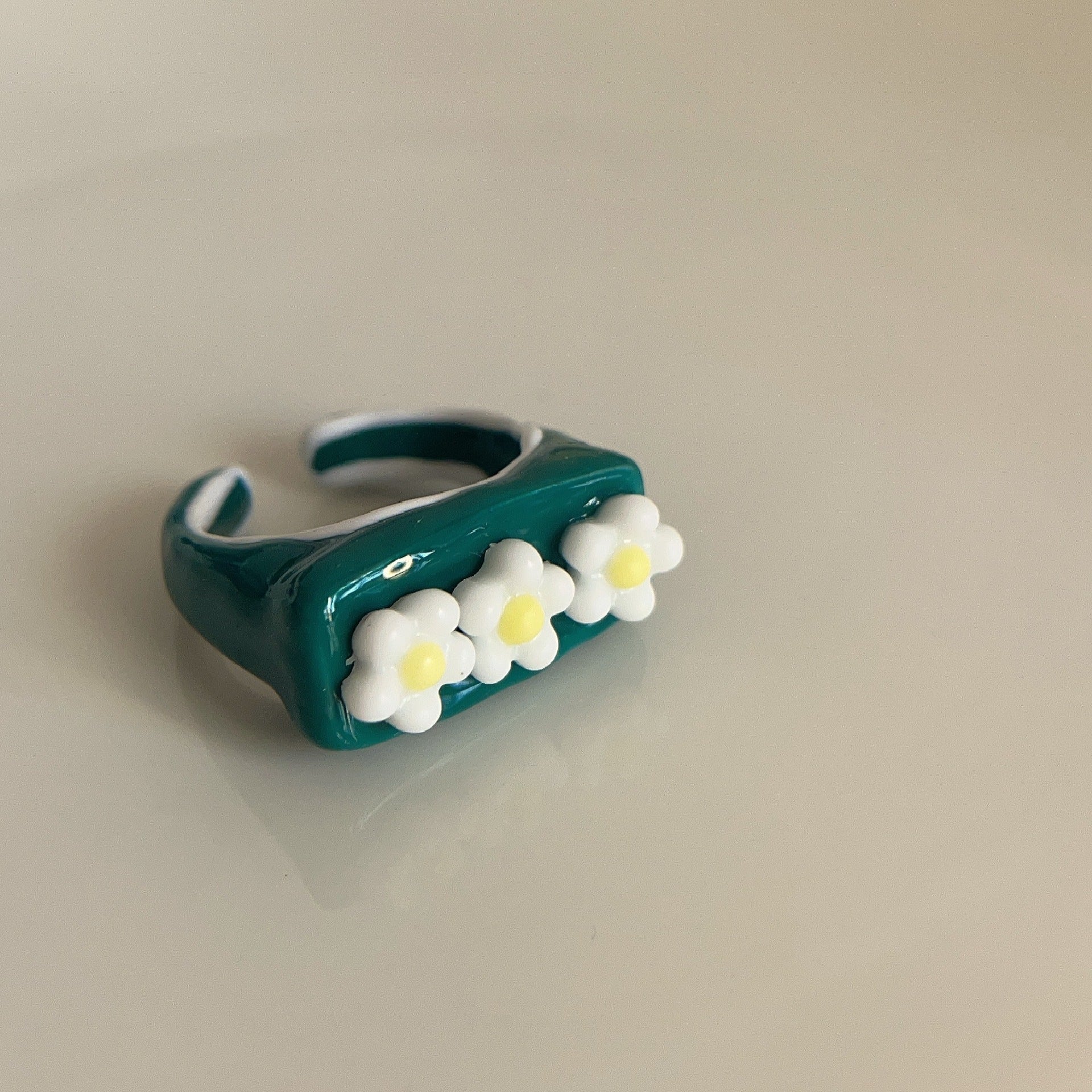 Teal ring with white flowers on a beige background