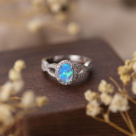 Silver ring with a blue opal stone on a wooden surface with dried flowers.