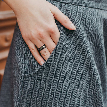 Hand with a ring on a gray textured fabric background