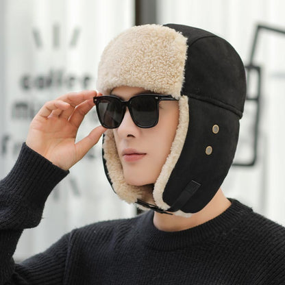 Person wearing a black and beige winter helmet with sunglasses, against a blurred indoor background.
