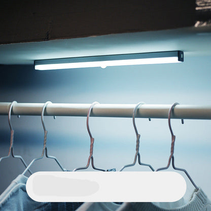 Under-cabinet LED light bar illuminating a clothing rack with hangers.