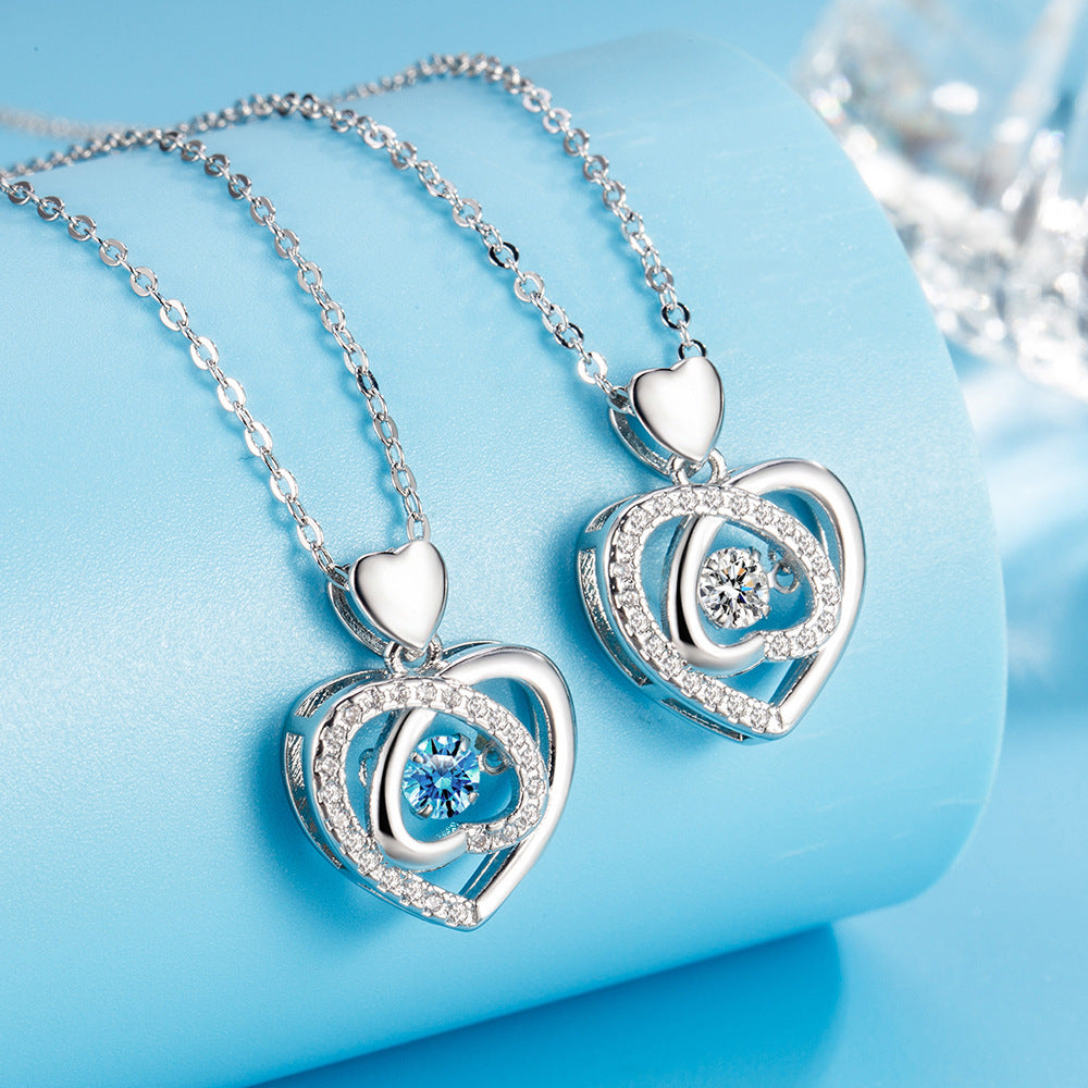 Heart-shaped silver pendants with blue gemstones on a light blue background