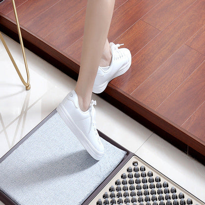 Person stepping onto a doormat with a wooden floor and chair in the background
