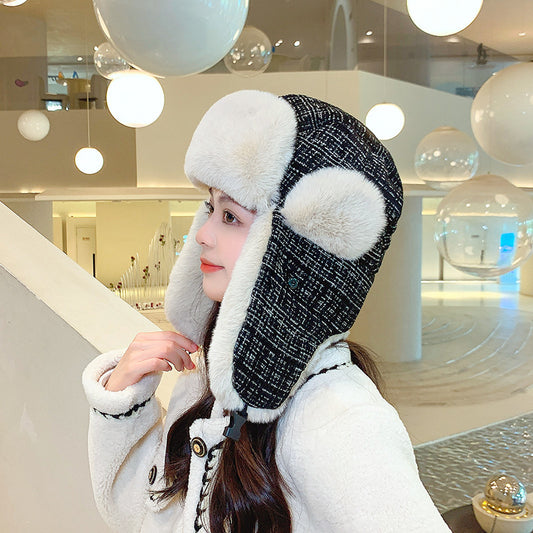 Person wearing a black and white winter hat with fur trim in an indoor setting.