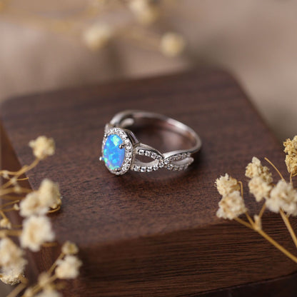 Silver ring with a blue gemstone on a wooden surface with dried flowers.