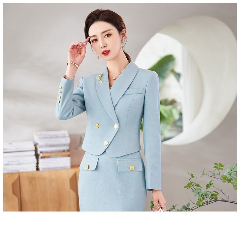 A woman in a white leisure formal suit with a blazer and a skirt, featuring long sleeves and gold buttons, standing outdoors.