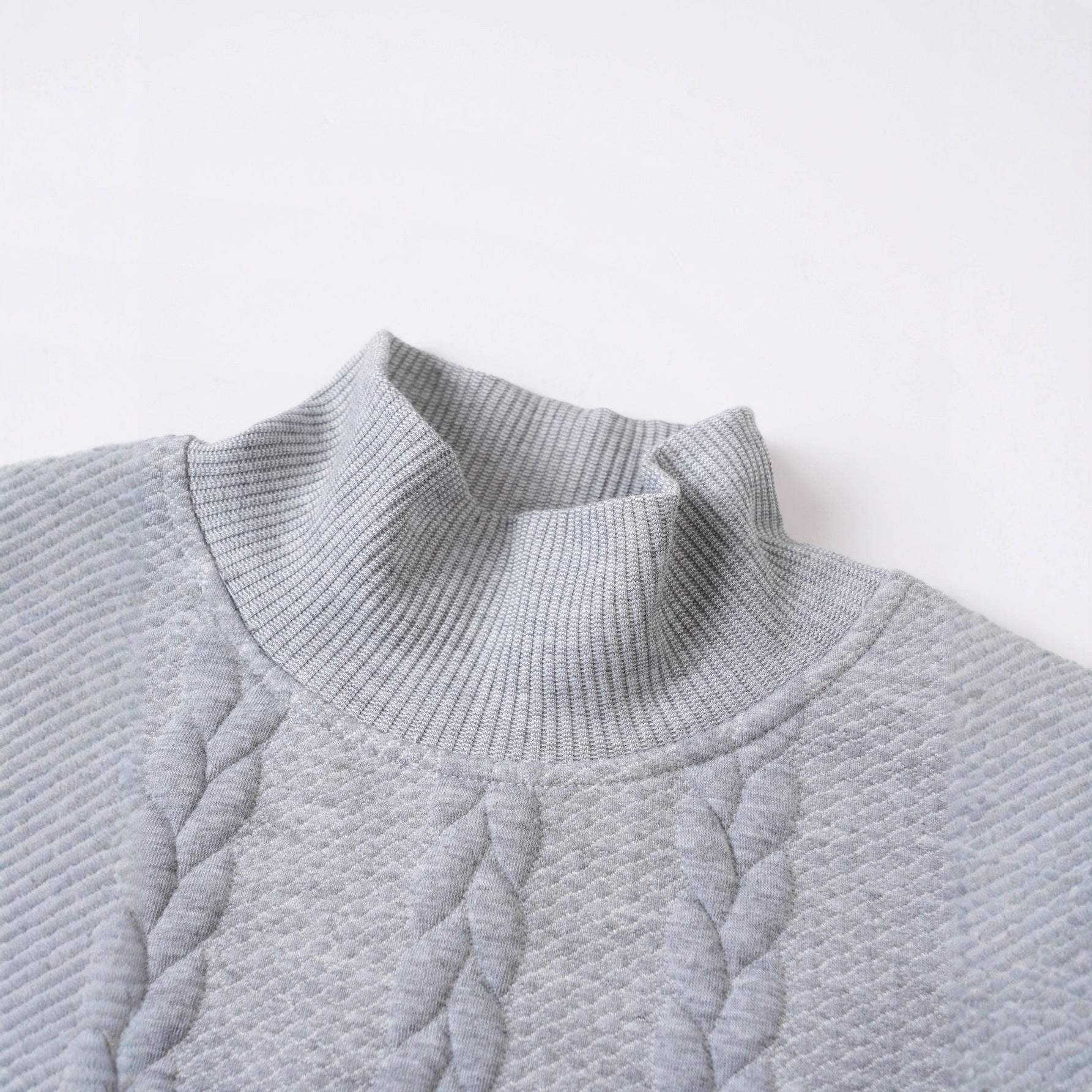 Close-up of a textured gray sweater on a light gray background