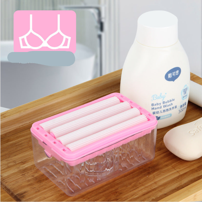 Pink and clear container with rolled-up pink items, next to a bottle of baby hand wash on a wooden surface.