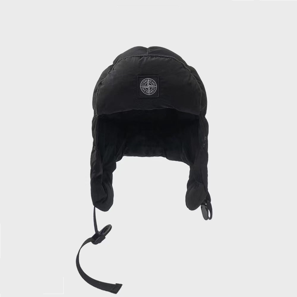 Black winter hat with ear flaps and a brand logo on a light gray background