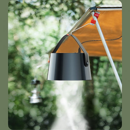 Black lamp hanging from a tent with a blurred green outdoor background