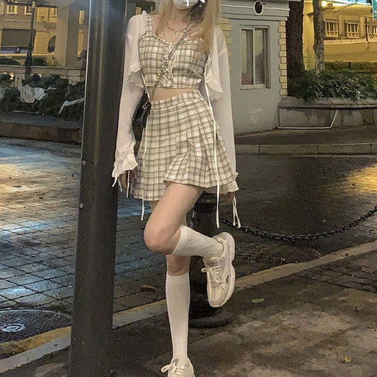 Person wearing a plaid dress and white sneakers on a city street.