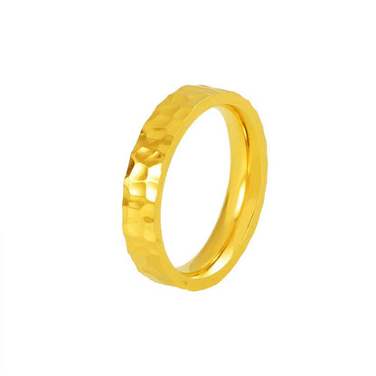 Gold ring with a textured design on a white background