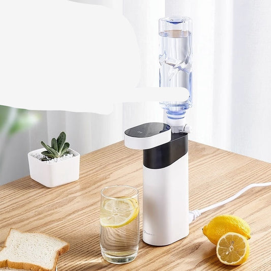 Water boiling device on a wooden table with a glass of water and lemon slices.